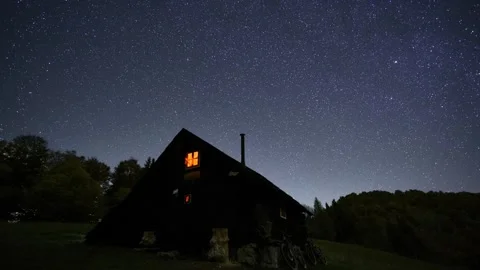 Peaceful starry night sky with countless stars above a wooden mountain hut in Stock Footage 319892662