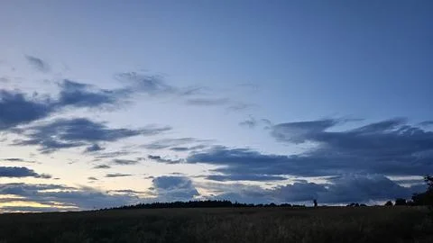 Peaceful sunset sky with dramatic clouds above open wheat fields, natural Stock Photos