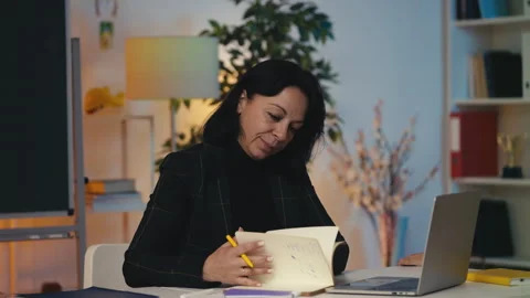 Peaceful teacher working at a desk while pupils run around, a pillar of calm Stockbeeldmateriaal 303139393
