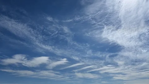 Peaceful time lapse of white summer circus clouds moving across a bright blue Stock Footage 337192957
