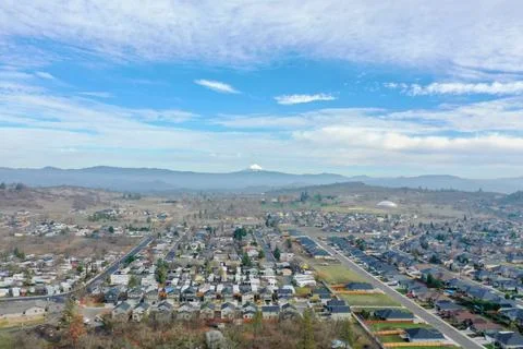 Peaceful town surrounded by trees with mountains as background Stock Photos
