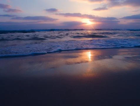 Peaceful view of a cloudy sunset on sandy beach with beautiful reflections 写真素材