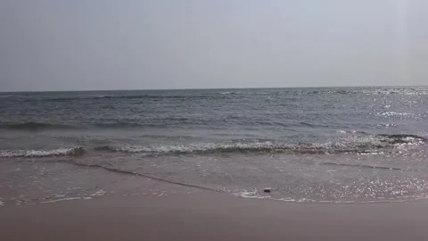 A peaceful view of the ocean waves gently rolling onto the sandy beach on a Vidéo 334163830