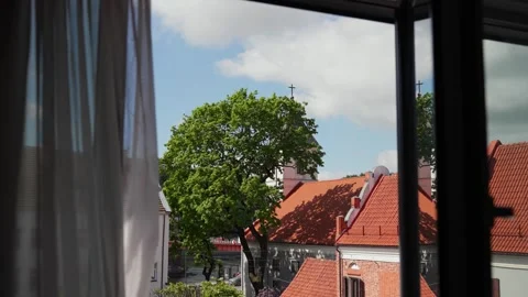Peaceful View of Quaint Red Roofs and Church Through Open Window on a Sunny Day Stock Footage 336385468