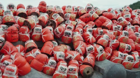 A peaceful view of red Daruma dolls at Katsuoji Temple, surrounded by lush Stock Footage 344280088