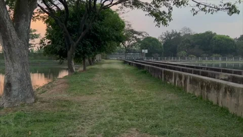 Peaceful walking path between tranquil lakes at sunset 스톡 동영상 336453122