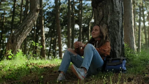 Peaceful Young woman sitting in pine forest and resting with eyes closed Stock Footage 135309853