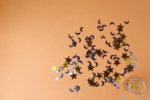 On a peach background, shiny confetti in the shape of the moon and stars. Foto stock