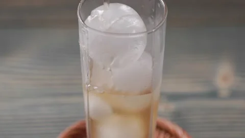 Peach Extract Juice Flowing Through Ice Cubes In Glass Close Up Vídeos de archivo 344050701