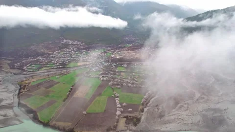 Peach lined fields and village emerging through Nyingchi clouds Stock Footage 345888497
