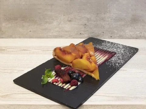 Peach pie served on a slate with creative cream sauce Stock Photos