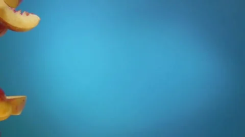 Peach slices fly down on a blue background Stock Footage 120032526