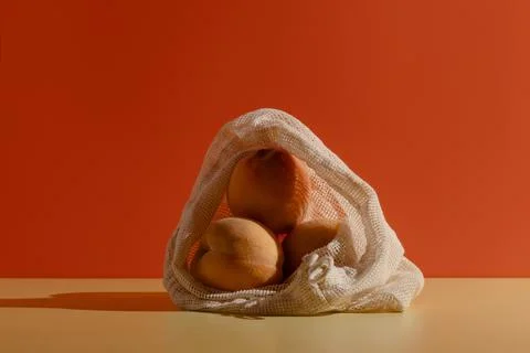 Peaches in a reusable cotton string bag on bright background Stock Photos