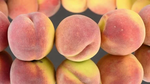 Peaches in a row on a black mirror. Clockwise rotation with acceleration. Stock Footage 161242545
