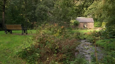 A Peak District scene with an old cottage, a bench and a stream Stock Footage 318261036