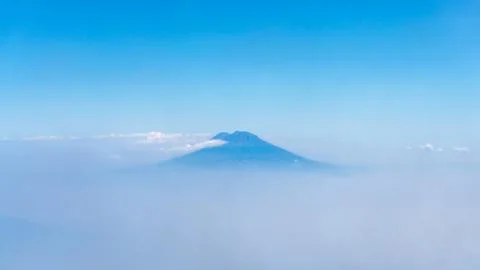 The peak of Mount Merapi above the clouds beneath a clear blue sky 写真素材