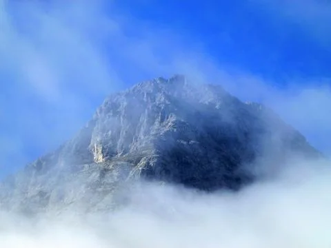 The peak of the mountain is covered with a cloud against the background Stock Photos
