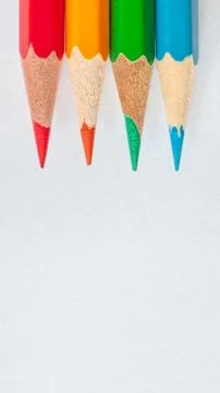 Peaks of four sharpened colored pencils on white paper vertical Stock Photos