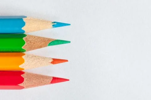 Peaks of four sharpened colored pencils on white paper Stock Photos