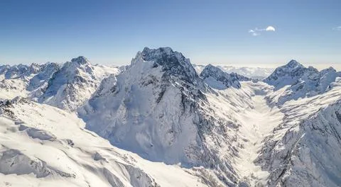 Peaks of the mountain range under the snow above the clouds Stock Photos
