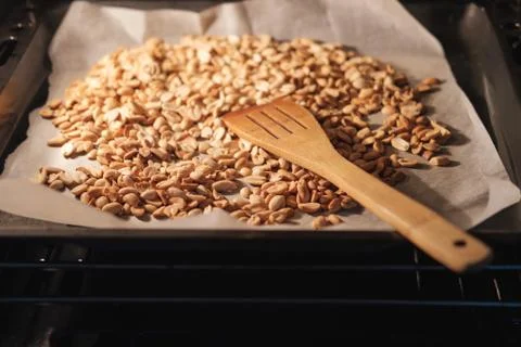 Peanut beans are fried on baking sheet and parchment paper in the oven Stock Photos