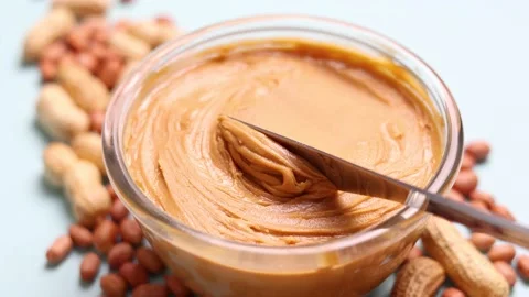 Peanut butter and raw peanuts on a colored background Stock Footage 238780663
