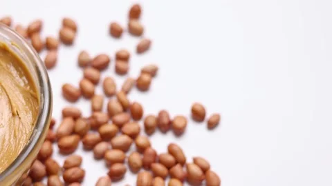 Peanut butter and raw peanuts on a light background Stock Footage 240666643