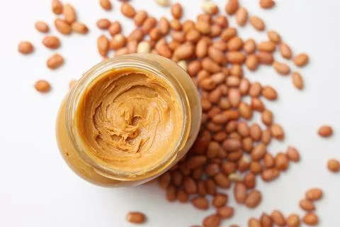 Peanut butter and raw peanuts on a light background Stock Photos