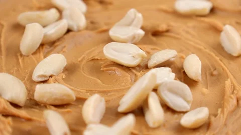 Peanut nuts falling down on peanut butter close up Stock Footage 276380740