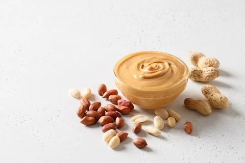 Peanut paste and nuts on white background for healthy nutrition concept. Stock Photos