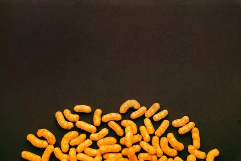 Peanut puff snacks on dark surface with empty copy space, minimalist food b.. Stock Photos