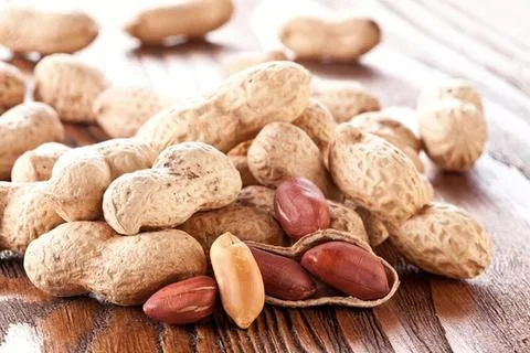 Peanuts and peanuts in shells on wooden surface Stock Photos