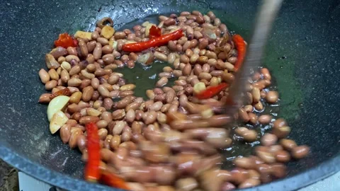 Peanuts are fried in a pan with garlic and curly red chilies; these peanuts are Stock Footage 328471825