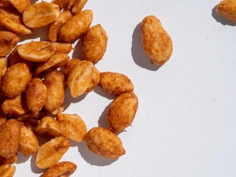 Peanuts are scattered on a white surface. Some peanuts are whole Stock Photos