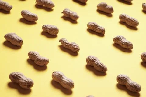 Peanuts arranged in rows on yellow background Stock Photos