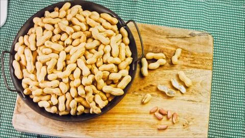 Peanuts with bark on a retro tray. Peanuts cleaned in the background. Slider Stock Photos