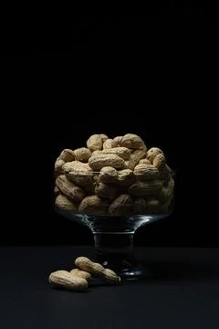 Peanuts on a black background. Glass with peanuts on a dark background.  Stock Photos