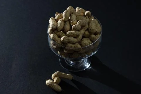 Peanuts on a black background. Glass with peanuts on a dark background Stock Photos