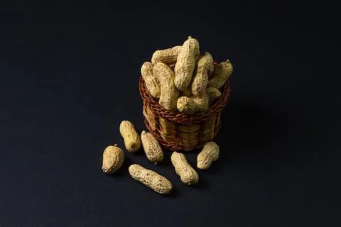 Peanuts on a black background. Peanuts in a small basket. Stock Photos
