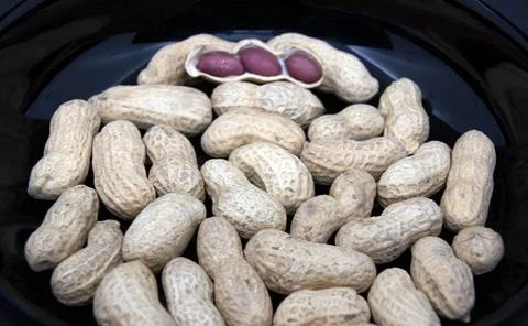 Peanuts in a black plate close up Stock Photos