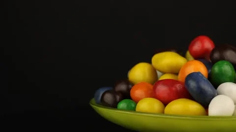 Peanuts in colored chocolate rotate on black background. 스톡 동영상 152656005