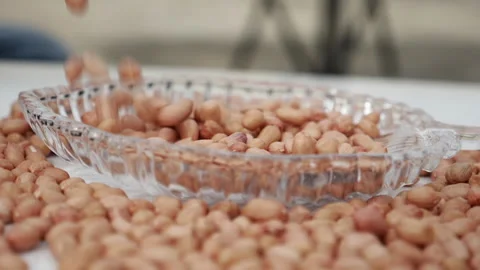 Peanuts fall from the top into a glass plate Stock Footage 139746425