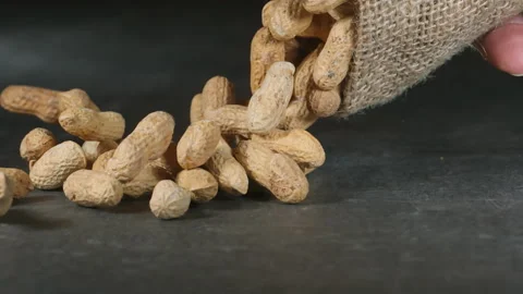 Peanuts falling from bag onto gray surface in super slow motion. Stock Footage 158453993