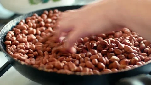 Peanuts groundnuts roasted in a pan and a woman stirs the nuts with her hand Stock Footage 133740245