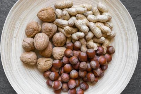 Peanuts, Hazelnuts and Walnuts with Nutshells Mix in Natural Bamboo Plate Stock Photos