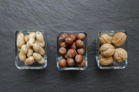 Peanuts, Hazelnuts and Walnuts with Nutshells Placed in Glass Plates Stock Photos