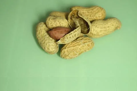 Peanuts isolated on a green background, macro photography Stock Photos