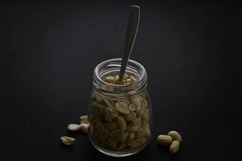 Peanuts in jar with spoon vertical composition on dark background Stock Photos