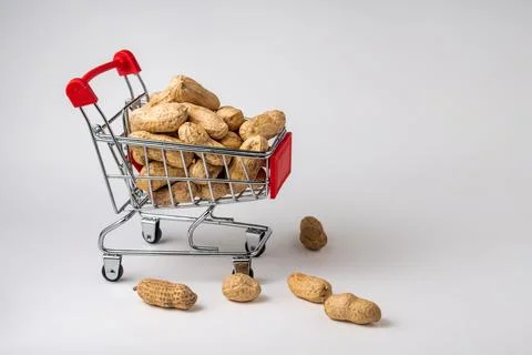 Peanuts in a nutshell in a shopping cart on a white background Stock Photos