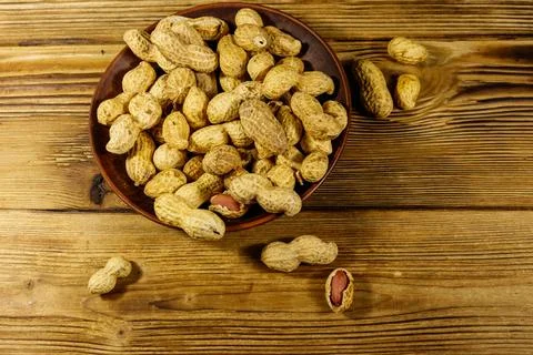 Peanuts in nutshell on a wooden table. Top view Stock Photos